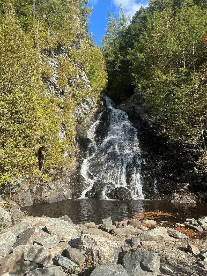 Waterfall over rocky ledges surrounded by early-autumn trees